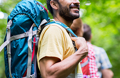 adventure, travel, tourism, hike and people concept - close up of friends walking with backpacks in woods