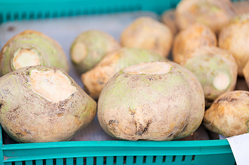 sale, harvest, food, vegetables and agriculture concept - close up of swede or turnip in plastic box at street market