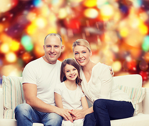 family, childhood, holidays and people concept - smiling mother, father and little girl over red lights background