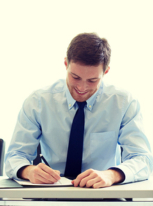 business, people and work concept - smiling businessman sitting and writing or signing papers in office