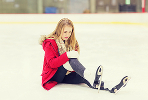 people, sport, trauma, pain and leisure concept - young woman fell down on skating rink and holding to her knee