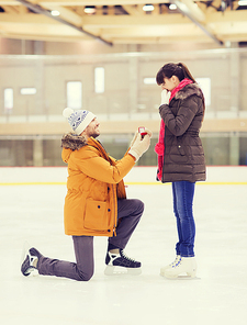people, love, proposal, sport and leisure concept - happy couple with engagement ring on skating rink