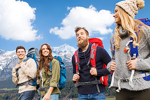 adventure, travel, tourism, hike and people concept - smiling friends walking with backpacks over mountains background