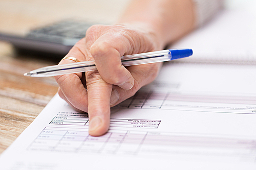 business, annuity insurance, age and people concept - close up of senior woman hand with pen checking bill