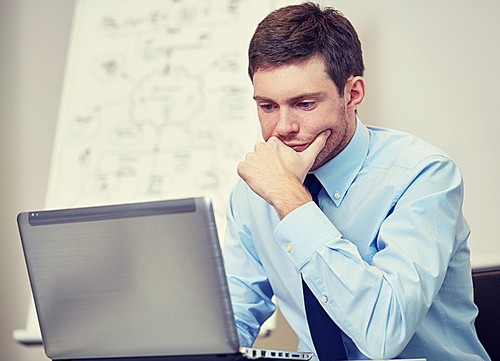 business, people and work concept - businessman sitting with laptop computer in office in front of whiteboard