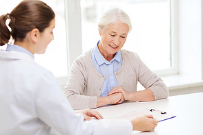 medicine, age, health care and people concept - doctor with clipboard and senior woman meeting at hospital