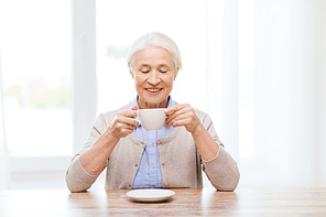 age, drink and people concept - happy smiling senior woman with cup of coffee at home