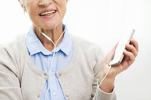 technology, age and people concept - close up of happy senior woman with smartphone and earphones listening to music at home