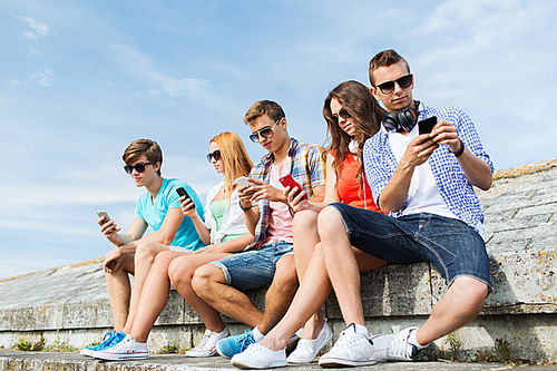 friendship, leisure, summer, technology and people concept - group of friends with smartphone outdoors