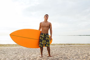 summer vacation and water sport concept - smiling young man with surfboard or stand up paddle board on beach