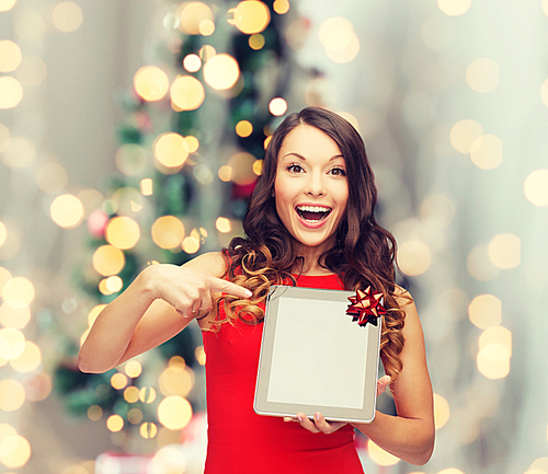 christmas, technology, present and people concept - smiling woman in red dress with blank tablet pc computer screen over living room and christmas tree background
