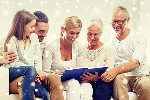 family, happiness, generation and people concept - happy family with book or photo album sitting on couch at home