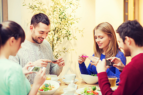 people, leisure, friendship and technology concept - group of happy friends with smartphones taking picture of food at cafe