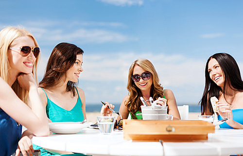 summer holidays and vacation - girls eating and  in cafe on the beach