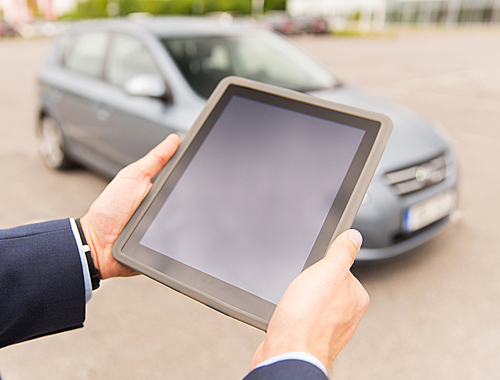 transport, business trip, technology and people concept - close up of young man with tablet pc computer on car parking