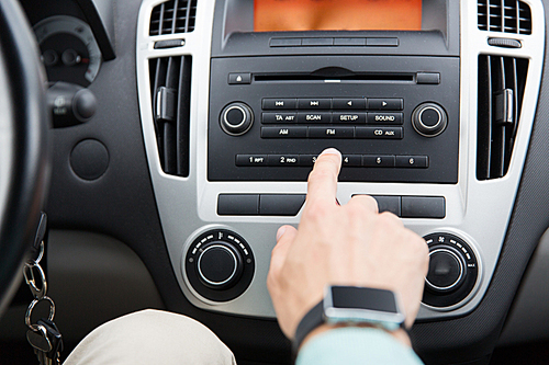 transport, road trip, car driving, technology and people concept - close up of male hand turning on radio on control panel system in car