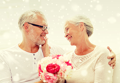 family, holidays, age and people concept - happy senior couple with bunch of flowers at home