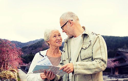 family, age, tourism, travel and people concept - senior couple with map and over asian village and mountains landscape background