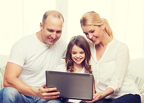 family, child, technology and home concept - smiling parents and little girl with laptop at home