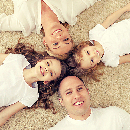family, children and home concept - smiling family with and two little girls lying in circle on floor at home