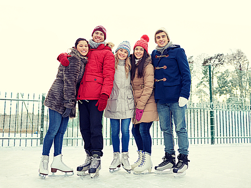 people, winter, friendship, sport and leisure concept - happy friends ice skating and hugging on rink outdoors