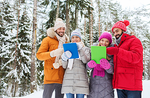 technology, season, friendship and people concept - group of smiling men and women with tablet pc computers in winter forest