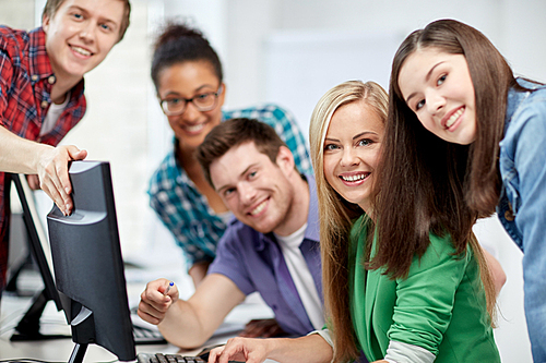 education, people, friendship, technology and learning concept - group of happy international high school students or classmates in computer class