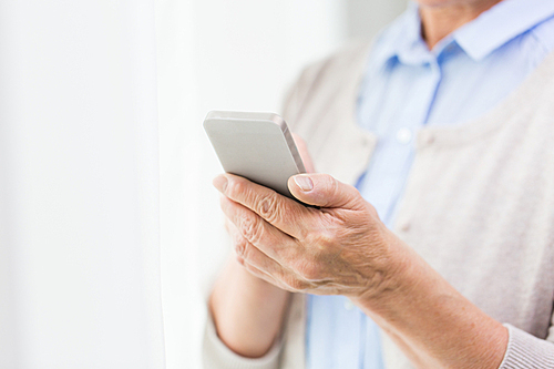 technology, communication age and people concept - close up of senior woman hands with smartphone texting message at home