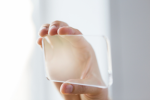 business, technology and people concept - close up of male hand holding and showing transparent smartphone at office