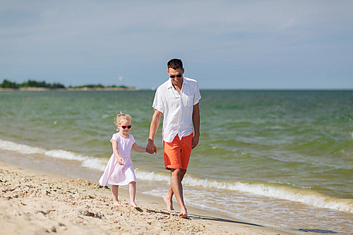 family, travel, vacation, adoption and people concept - happy father with little girl in sunglasses walking on summer beach