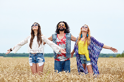 nature, summer, youth culture and people concept - smiling young hippie friends on cereal field enjoying freedom