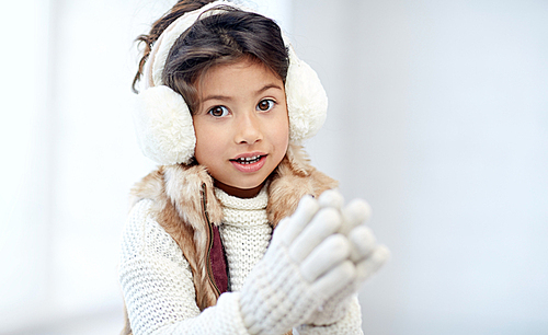 winter, people, happiness concept - happy little girl wearing earmuffs