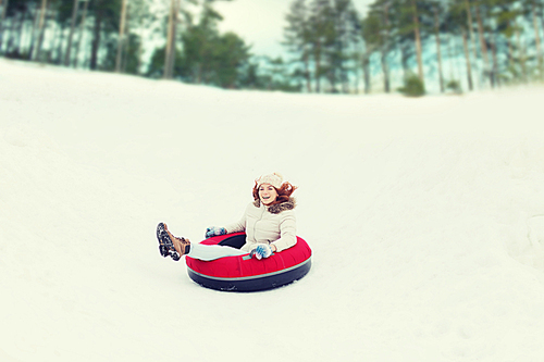 winter, leisure, sport, and people concept - happy teenage girl or woman sliding down on snow tube