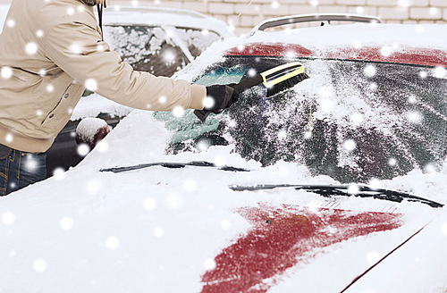 transportation, winter, people and vehicle concept - closeup of man cleaning snow from car windshield with brush