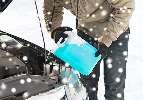 transportation, winter, people and vehicle concept - closeup of man pouring antifreeze into car