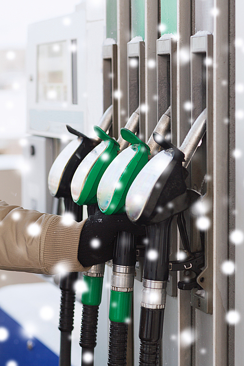 transportation, tanking, people and vehicle concept - close up of man holding fuel hose nozzle at gas station