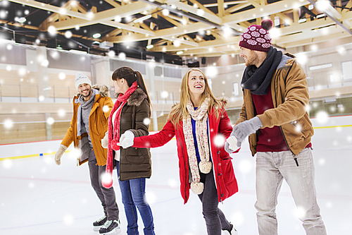 people, friendship, sport and leisure concept - happy friends on skating rink