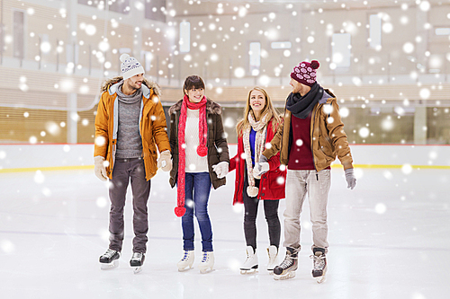 people, friendship, sport and leisure concept - happy friends on skating rink