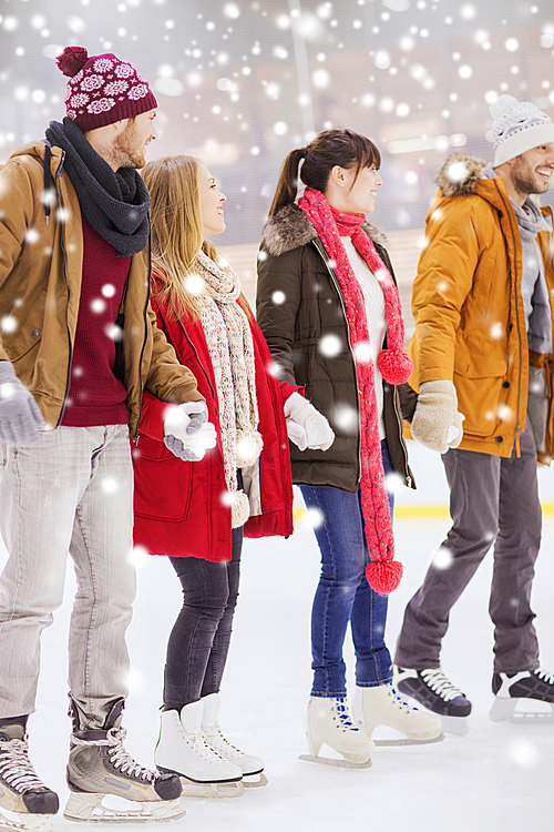 people, friendship, sport and leisure concept - happy friends on skating rink