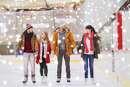 people, friendship, sport and leisure concept - happy friends on skating rink