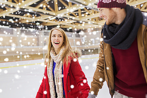 people, friendship, sport and leisure concept - happy couple holding hands on skating rink