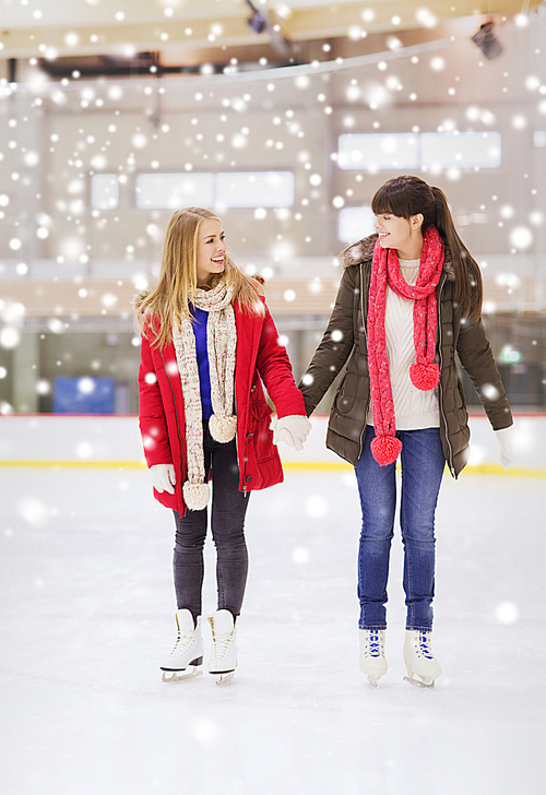 people, women, friendship, sport and leisure concept - two happy girls friends on skating rink