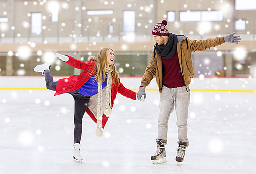 people, friendship, sport and leisure concept - happy couple holding hands on skating rink