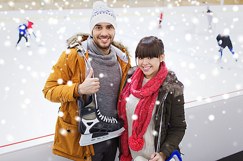 people, friendship, sport and leisure concept - happy couple with ice-skates on skating rink