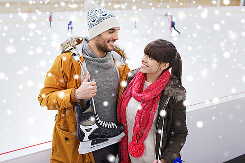 people, friendship, sport and leisure concept - happy couple with ice-skates on skating rink