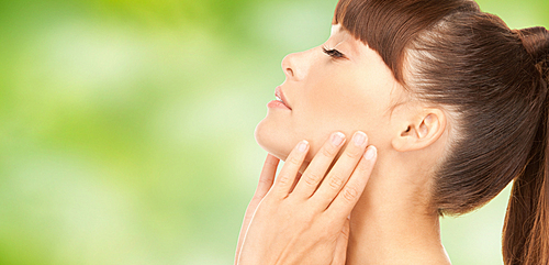 beauty, people, body care and health concept - beautiful young woman face over green natural background