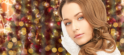 winter holidays, christmas and people concept - young woman in white cloves over lights background