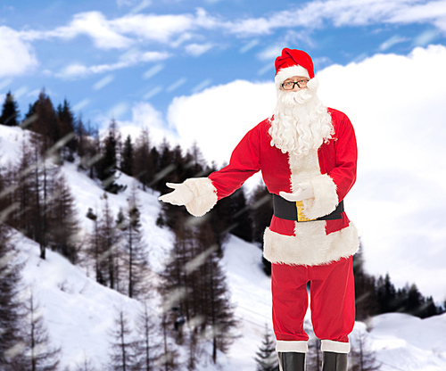 christmas, holidays, gesture and people concept - man in costume of santa claus over snowy mountains background