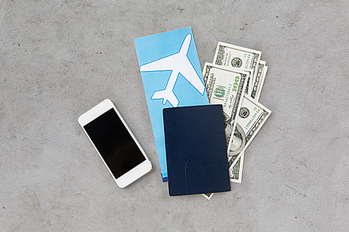 tourism, travel and objects concept - air ticket, money, smartphone and passport over gray concrete background