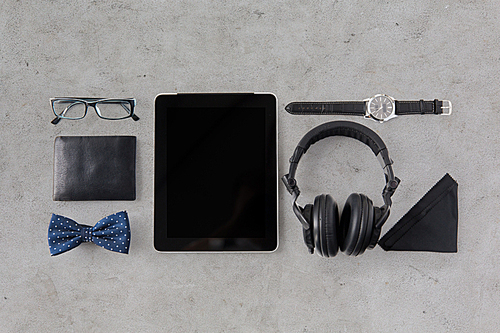 hipster personal stuff and objects concept - tablet pc computer, headphones, wallet, eyeglasses and wristwatch over gray concrete background